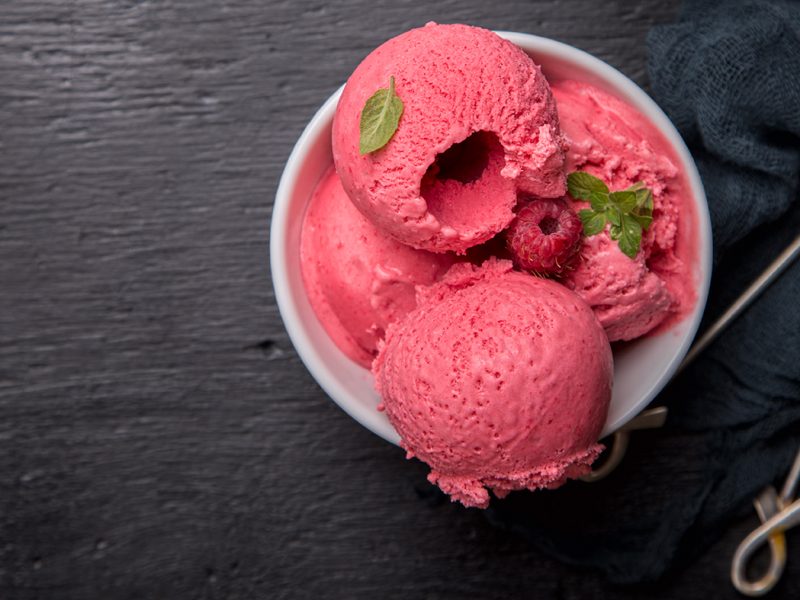 Ice cream Raspberry  in white bowl on the black background.Dessert.Copy space for Text.Sorbet In the form of a ball.selective focus.